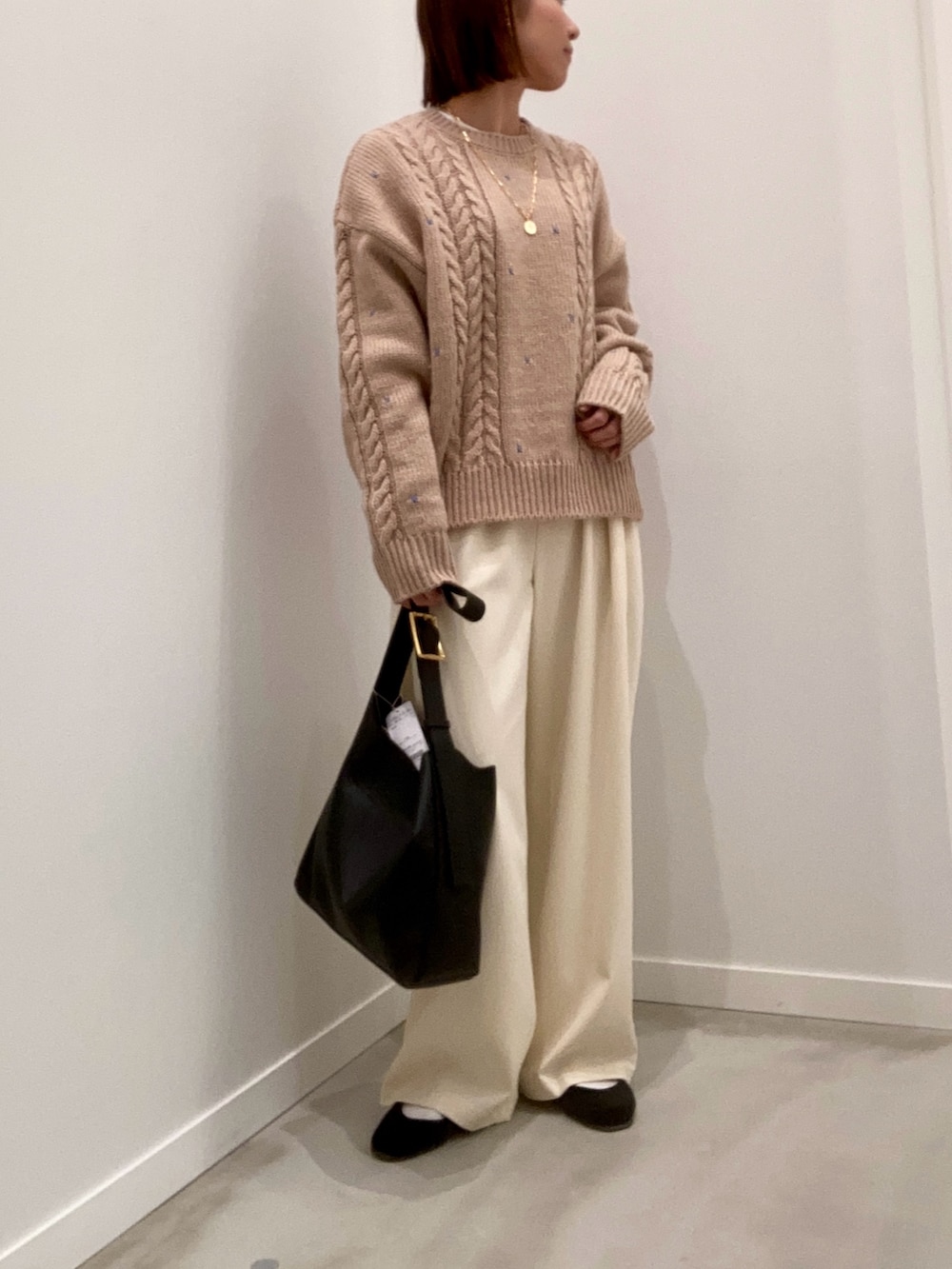 ベージュ系のニット/セーター、ホワイト系のTシャツ/カットソー、ブラック系のショルダーバッグを着用したレディースの秋コーディネートの2枚目の写真