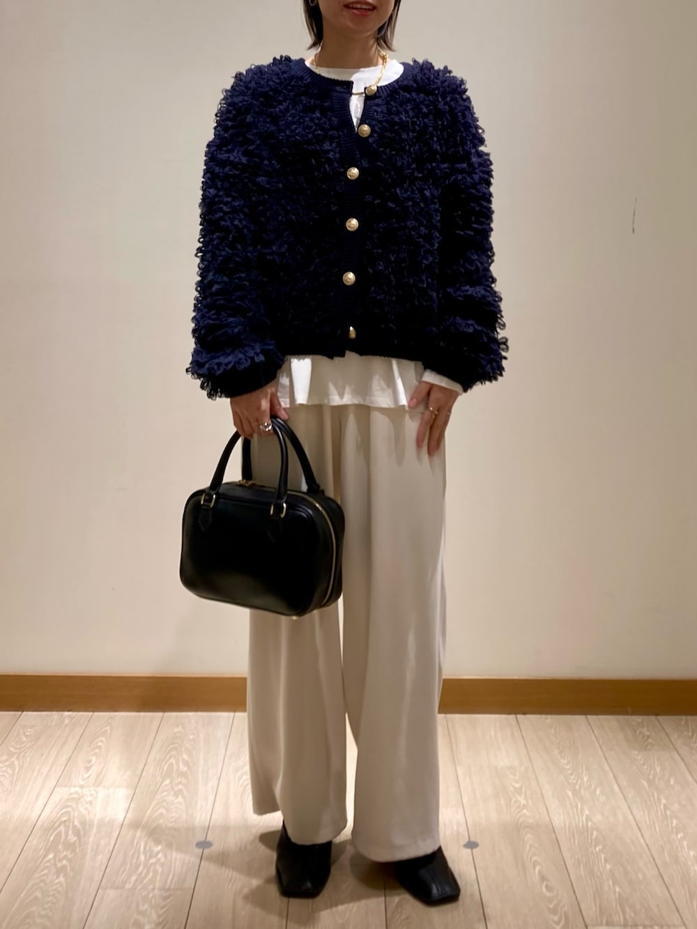 ブルー系のカーディガン/ボレロ、ブラック系のハンドバッグ、ホワイト系のTシャツ/カットソーを着用したレディースの冬コーディネートの2枚目の写真