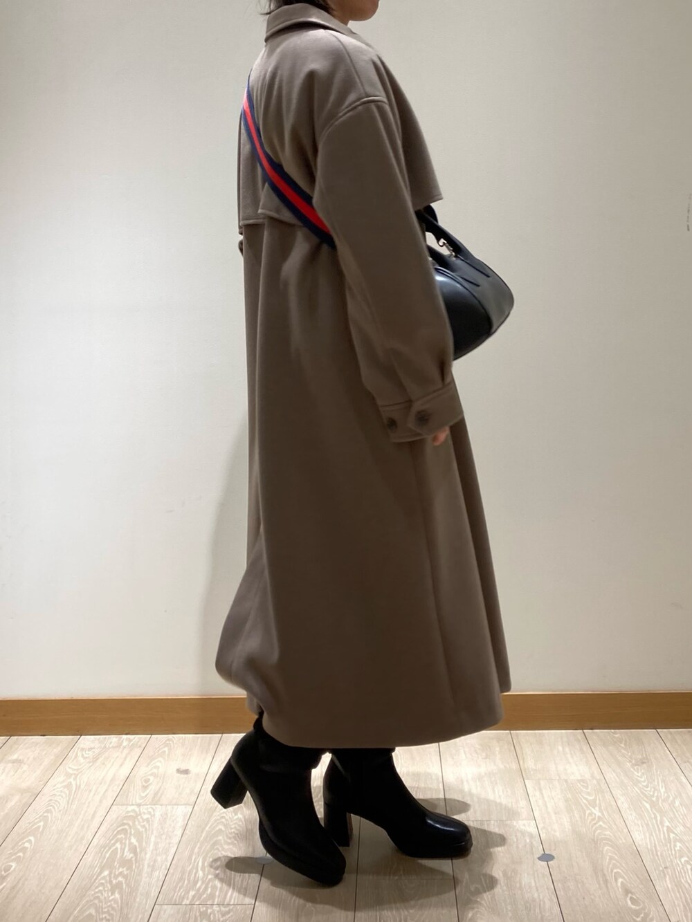 ブラウン系のステンカラーコート、ブラック系のボストンバッグ、ブラック系のブーツを着用したレディースの冬コーディネートの5枚目の写真