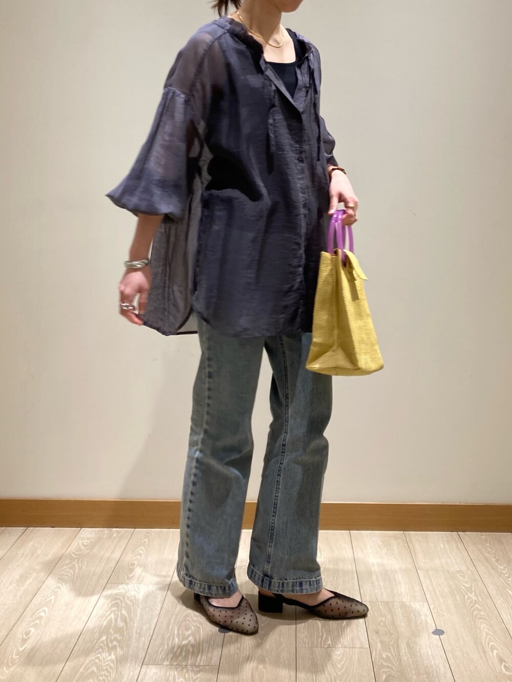 イエロー系のかごバッグ、ブルー系のデニムパンツ、ブラック系のパンプスを着用したレディースの春コーディネートの4枚目の写真