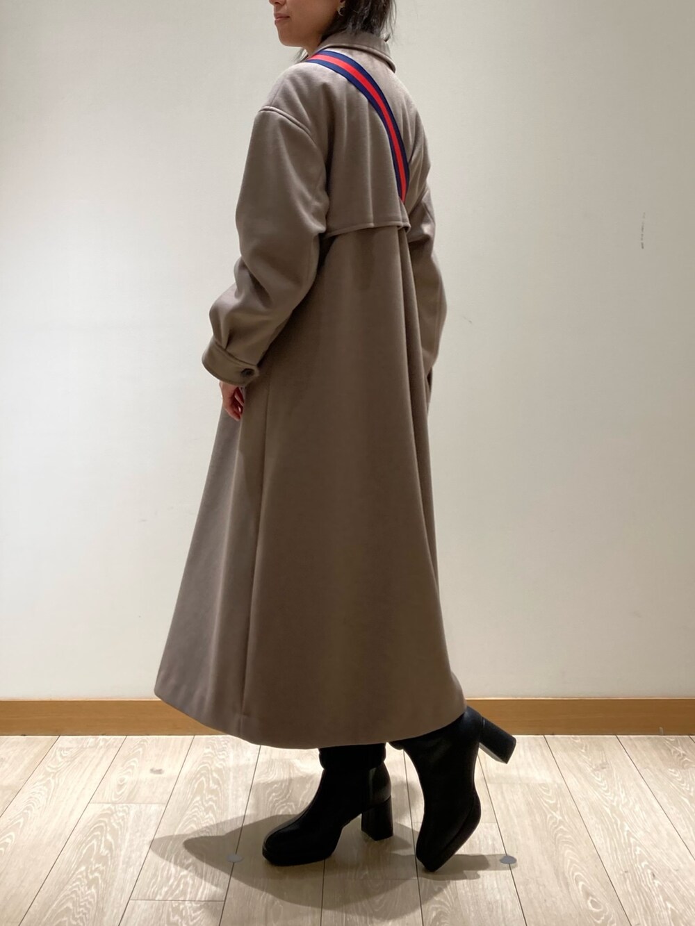 ブラウン系のステンカラーコート、ブラック系のボストンバッグ、ブラック系のブーツを着用したレディースの冬コーディネートの6枚目の写真