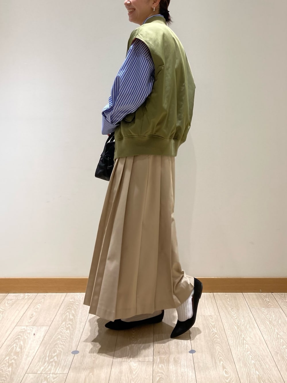 グリーン系のブルゾン、ブルー系のシャツ/ブラウス、ベージュ系のスカートを着用したレディースの冬コーディネートの2枚目の写真