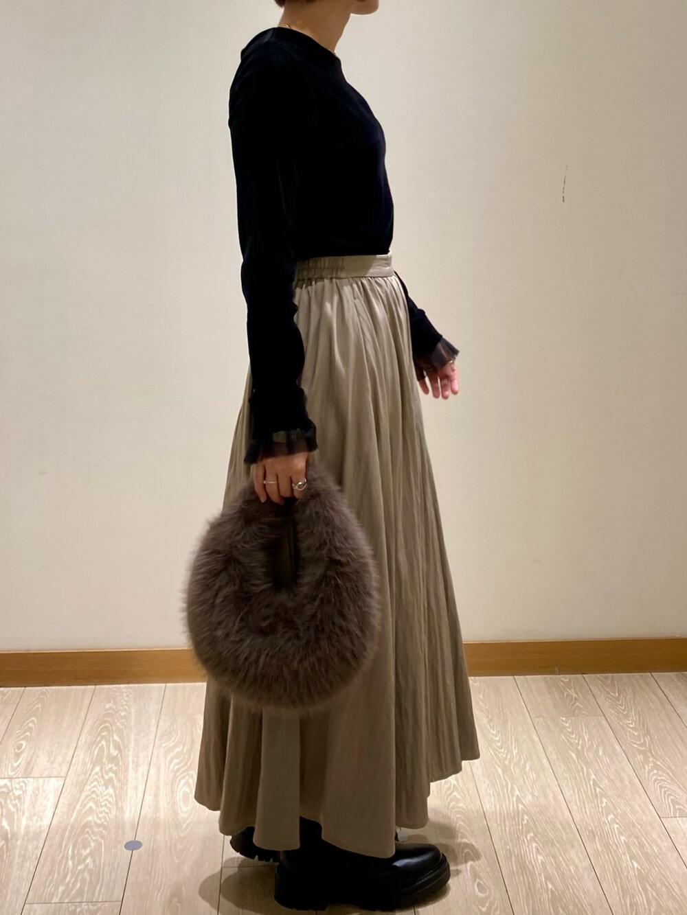 グレー系のハンドバッグ、ブラック系のブーツ、ブラック系のTシャツ/カットソーを着用したレディースの秋コーディネートの3枚目の写真