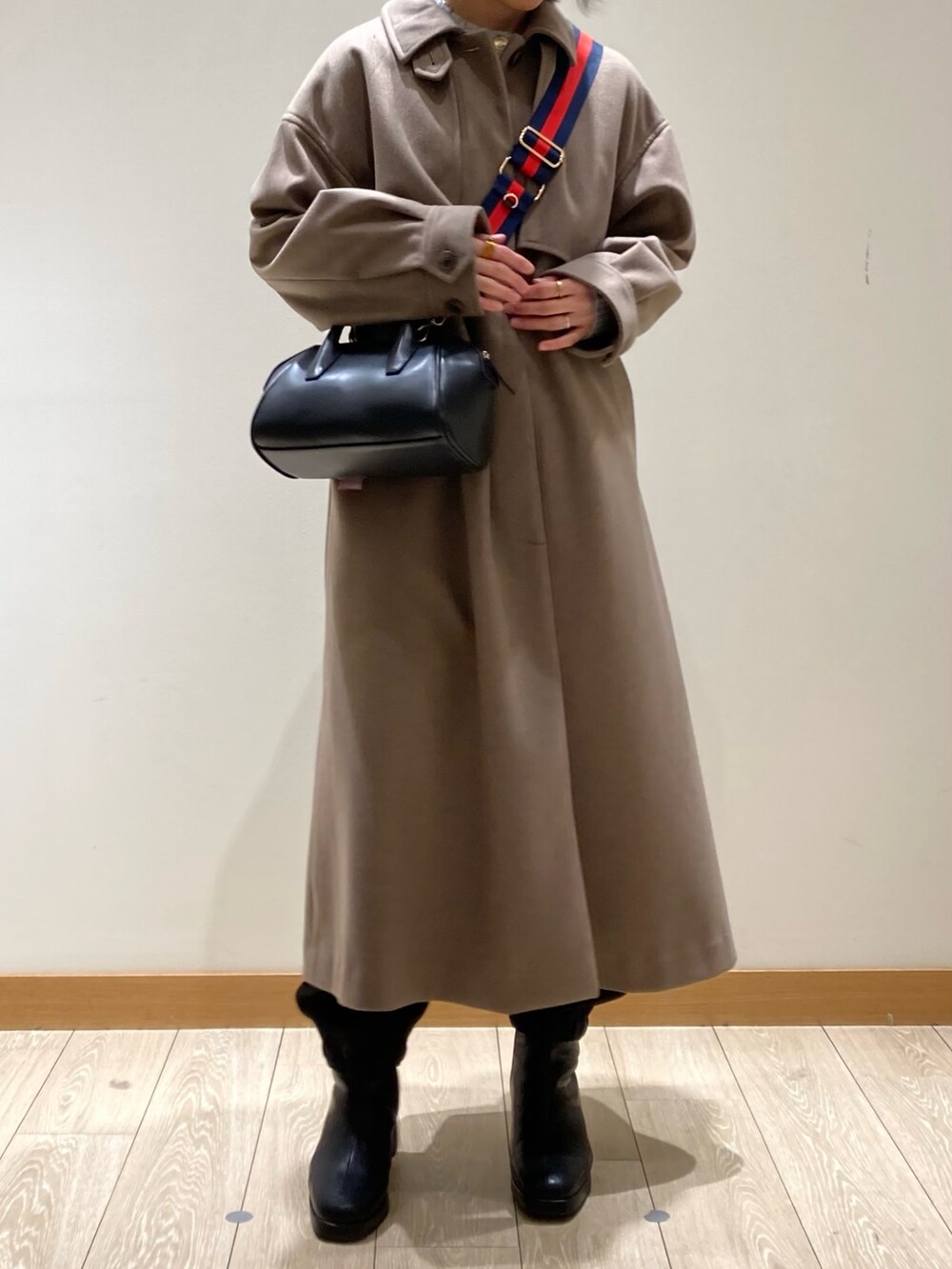 ブラウン系のステンカラーコート、ブラック系のボストンバッグ、ブラック系のブーツを着用したレディースの冬コーディネートの8枚目の写真