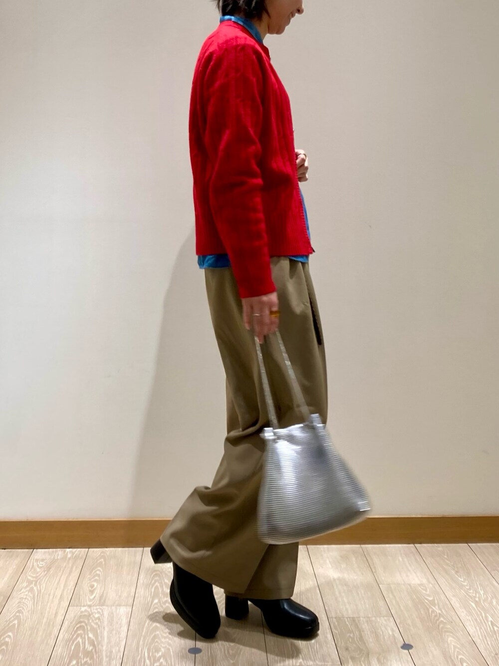 レッド系のカーディガン/ボレロ、ブラック系のブーツ、ベージュ系のスラックスを着用したレディースの冬コーディネートの3枚目の写真