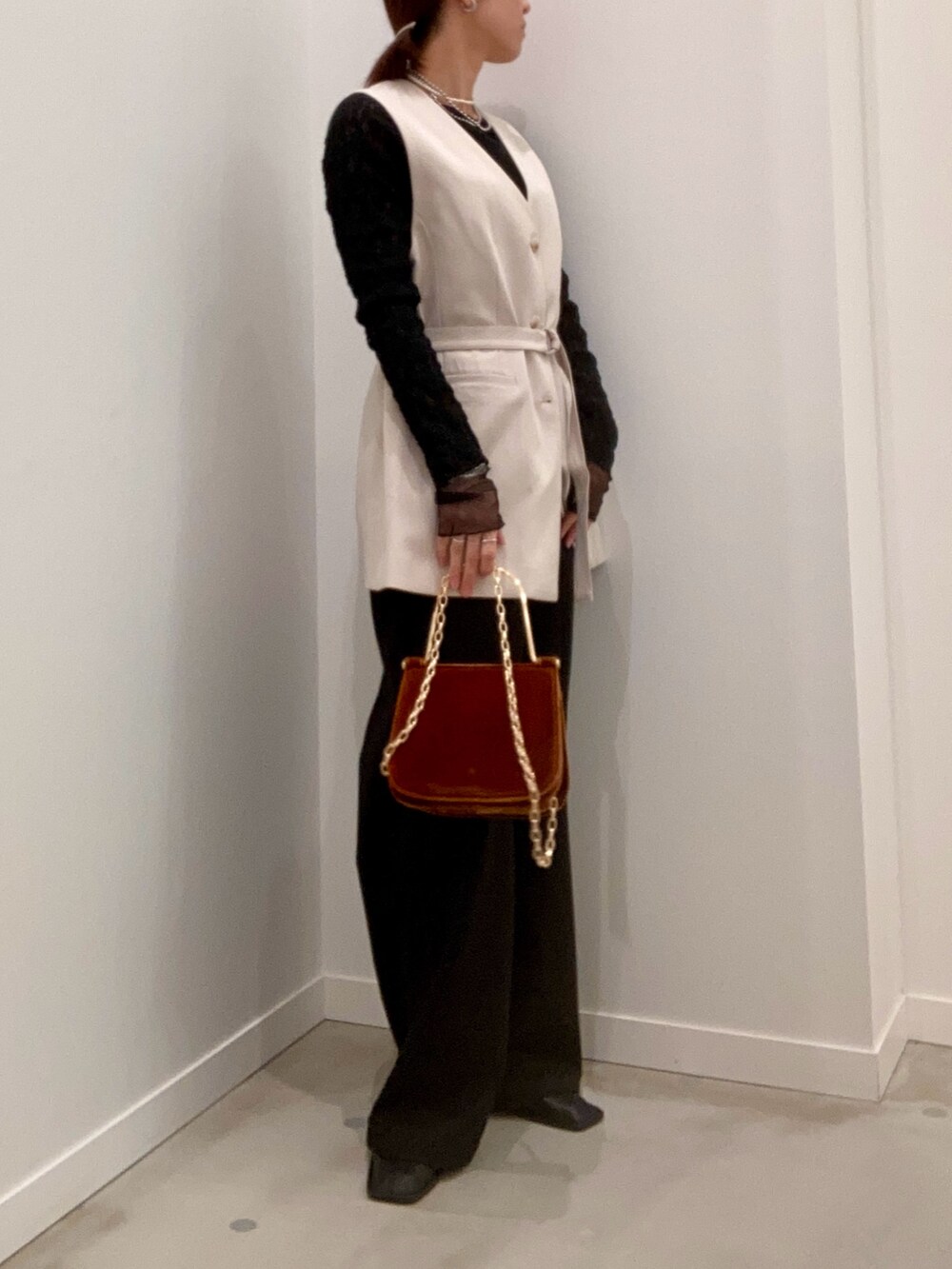 ベージュ系のベスト、ブラック系のTシャツ/カットソー、ブラウン系のショルダーバッグを着用したレディースの冬コーディネートの4枚目の写真