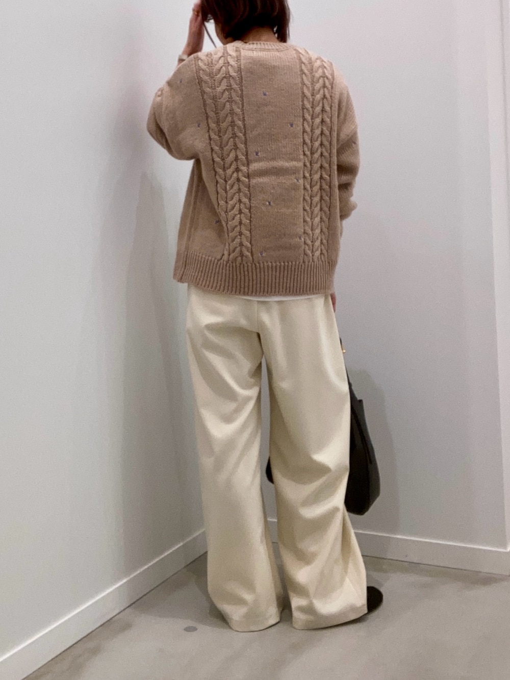 ベージュ系のニット/セーター、ホワイト系のTシャツ/カットソー、ブラック系のショルダーバッグを着用したレディースの秋コーディネートの4枚目の写真