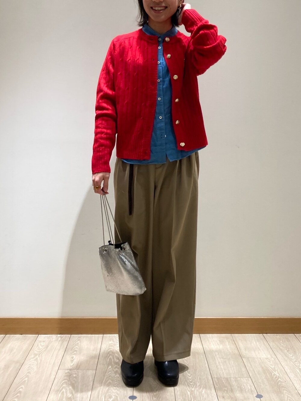 レッド系のカーディガン/ボレロ、ブラック系のブーツ、ベージュ系のスラックスを着用したレディースの冬コーディネートの2枚目の写真