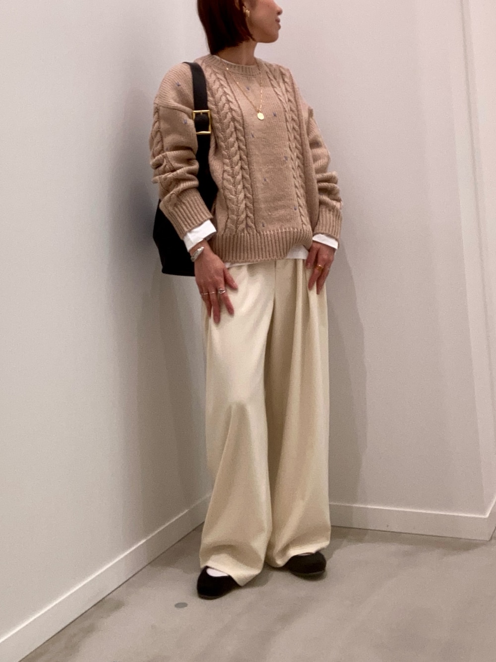 ベージュ系のニット/セーター、ホワイト系のTシャツ/カットソー、ブラック系のショルダーバッグを着用したレディースの秋コーディネートの7枚目の写真