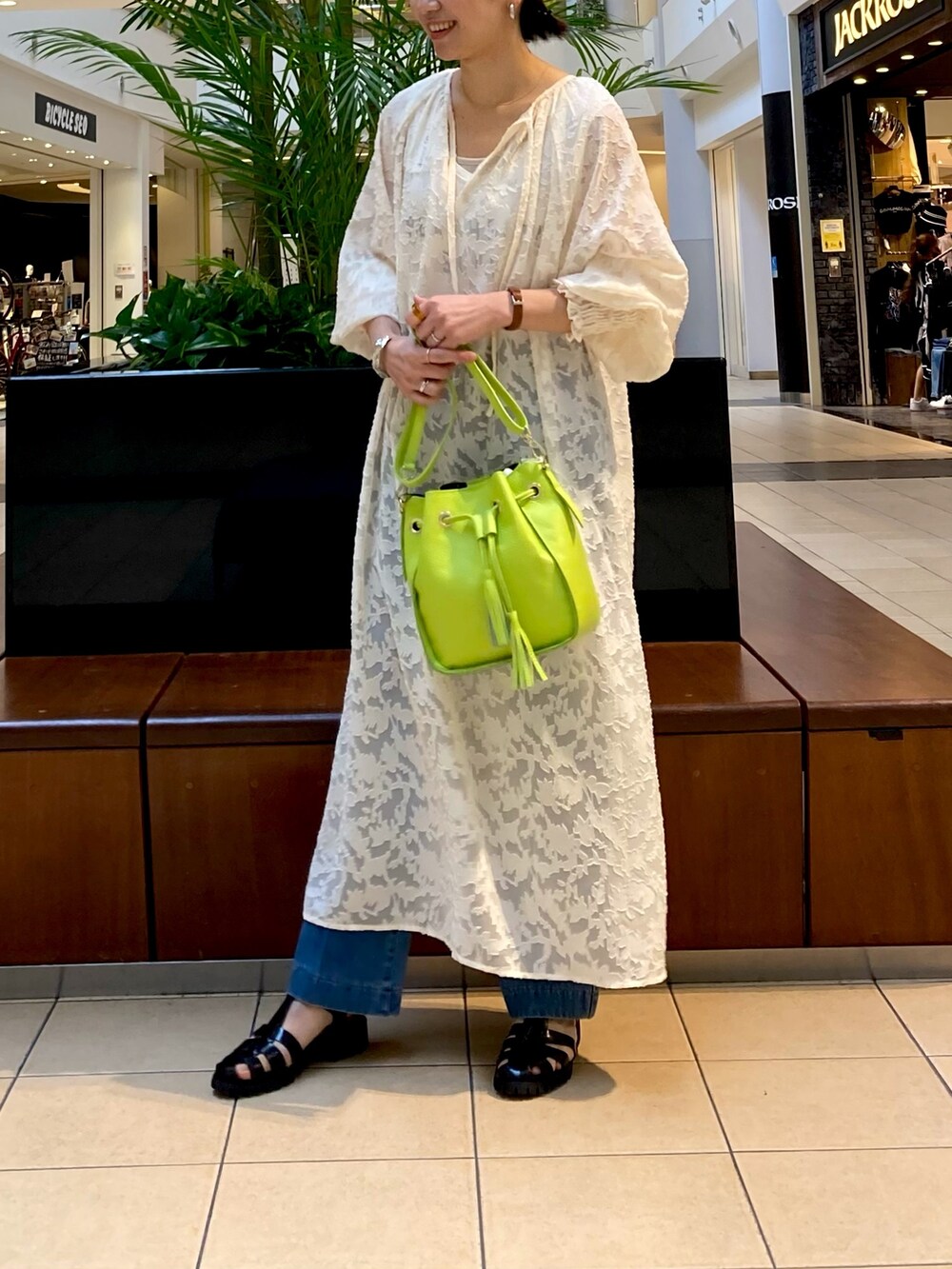 ホワイト系のワンピース、ブラック系のサンダル、ブルー系のデニムパンツを着用したレディースの春コーディネートの2枚目の写真