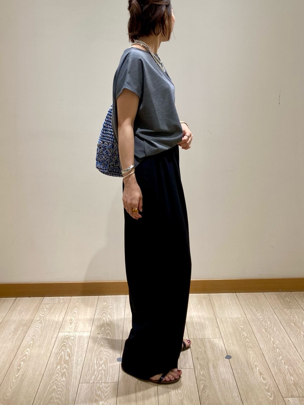 グレー系のTシャツ/カットソー、ブルー系のかごバッグ、ブラック系のその他パンツを着用したレディースの夏コーディネートの4枚目の写真