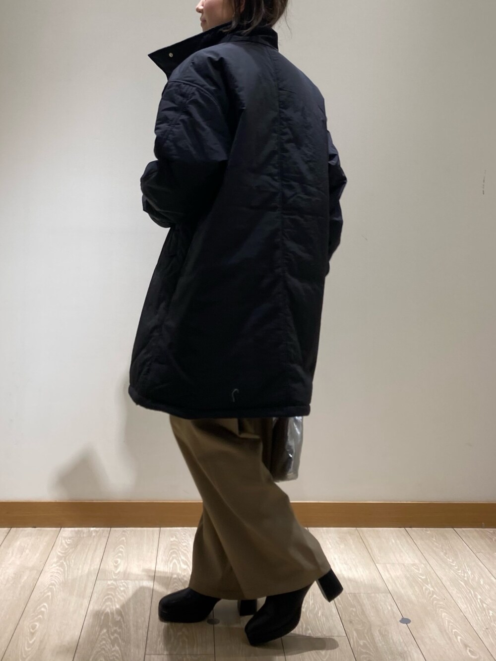ベージュ系のスラックス、シルバー系のショルダーバッグ、ブラック系のブーツを着用したレディースの冬コーディネートの4枚目の写真