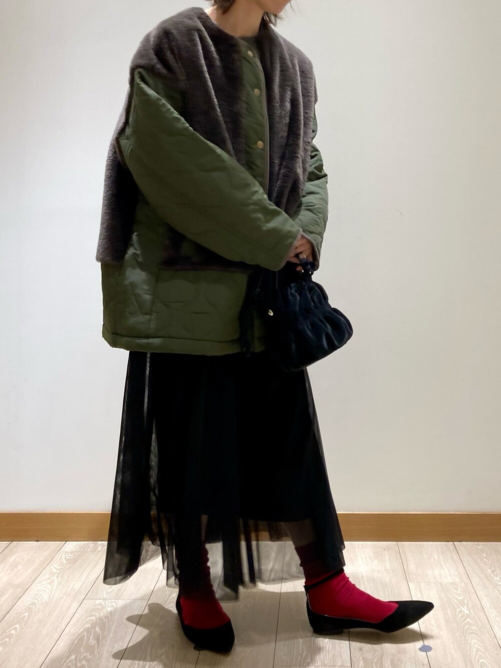 ブラック系のショルダーバッグ、ブラック系のワンピース、グリーン系のブルゾンを着用したレディースの冬コーディネートの3枚目の写真