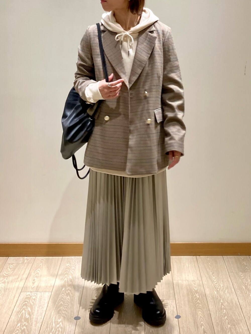 シルバー系のスカート、ベージュ系のテーラードジャケット、ホワイト系のパーカーを着用したレディースの秋コーディネートの6枚目の写真