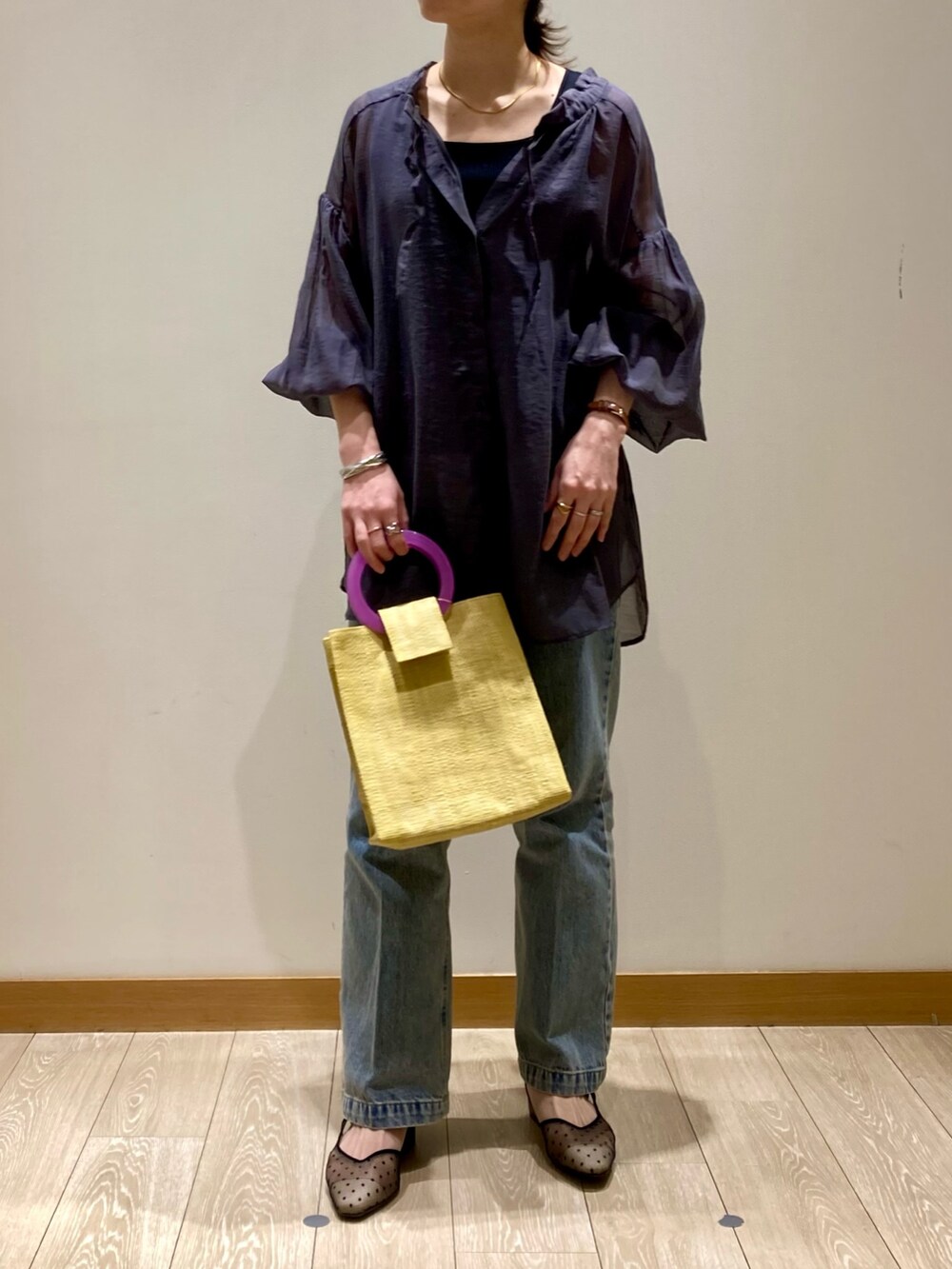 イエロー系のかごバッグ、ブルー系のデニムパンツ、ブラック系のパンプスを着用したレディースの春コーディネートの7枚目の写真