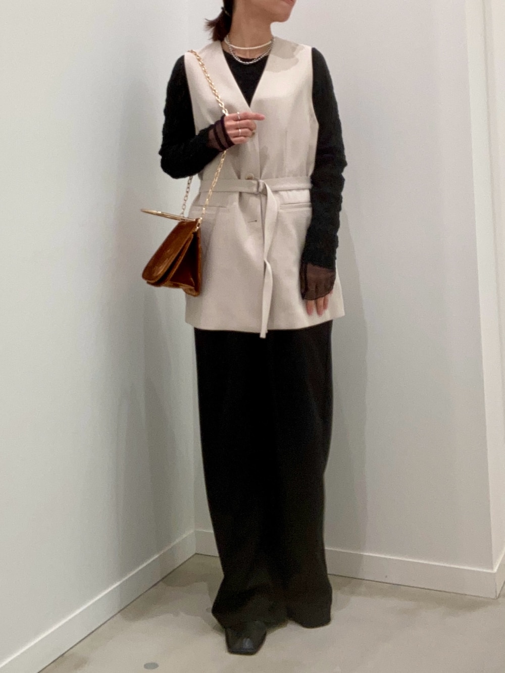 ベージュ系のベスト、ブラック系のTシャツ/カットソー、ブラウン系のショルダーバッグを着用したレディースの冬コーディネートの2枚目の写真