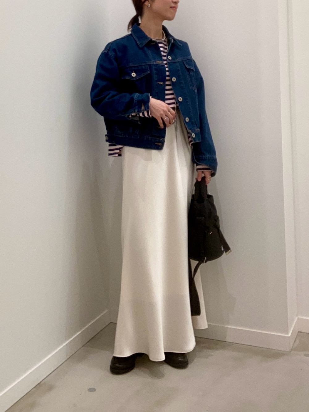 ブルー系のデニムジャケット、ホワイト系のスカート、ブラック系のその他シューズを着用したレディースの冬コーディネートの2枚目の写真