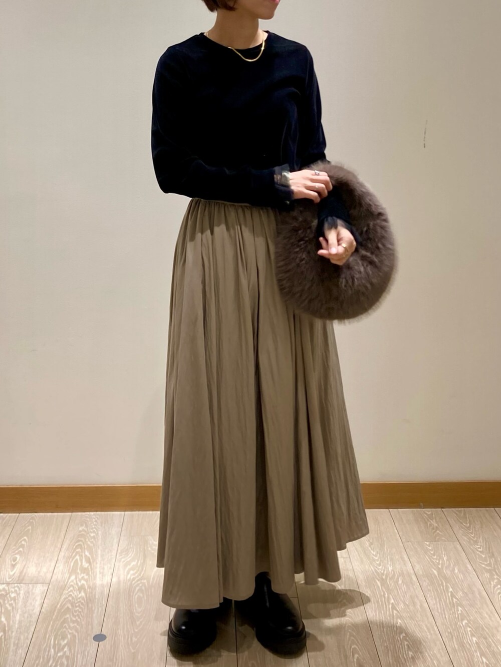 グレー系のハンドバッグ、ブラック系のブーツ、ブラック系のTシャツ/カットソーを着用したレディースの秋コーディネートの2枚目の写真