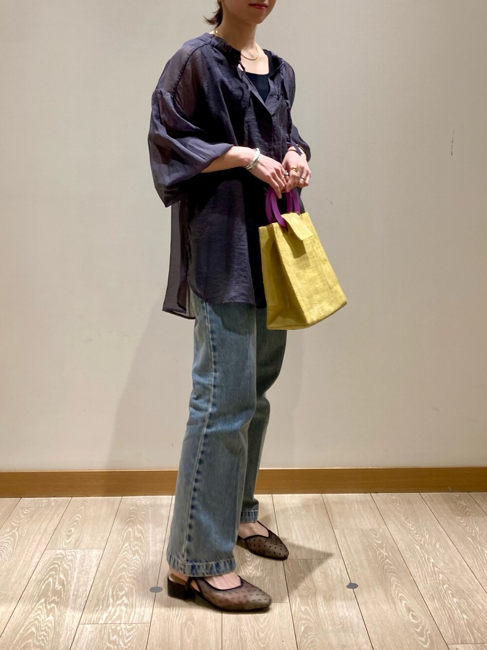 イエロー系のかごバッグ、ブルー系のデニムパンツ、ブラック系のパンプスを着用したレディースの春コーディネートの3枚目の写真