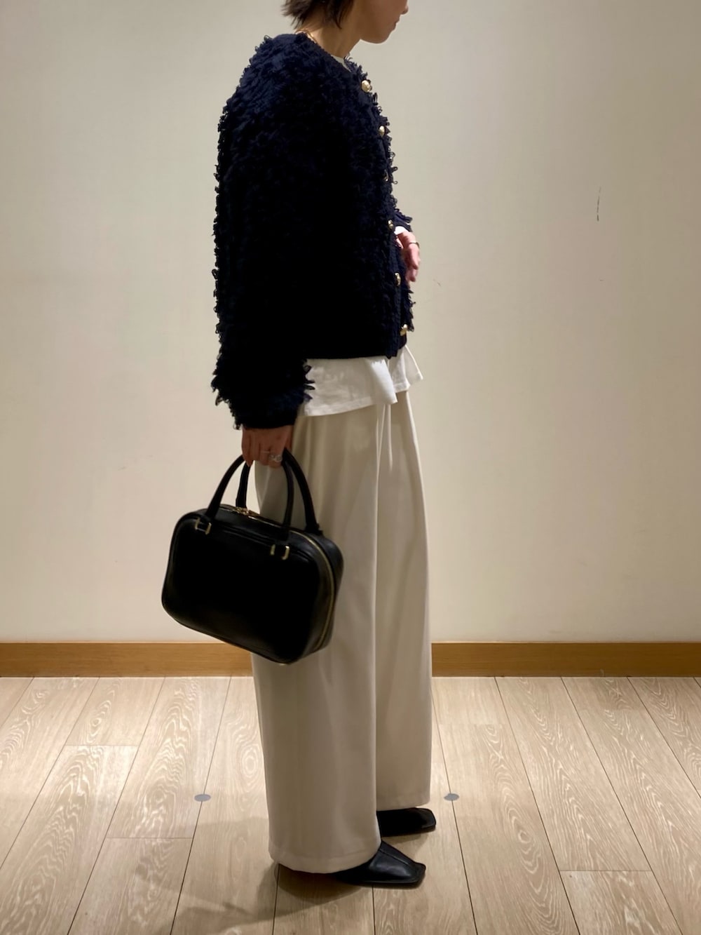 ブルー系のカーディガン/ボレロ、ブラック系のハンドバッグ、ホワイト系のTシャツ/カットソーを着用したレディースの冬コーディネートの4枚目の写真