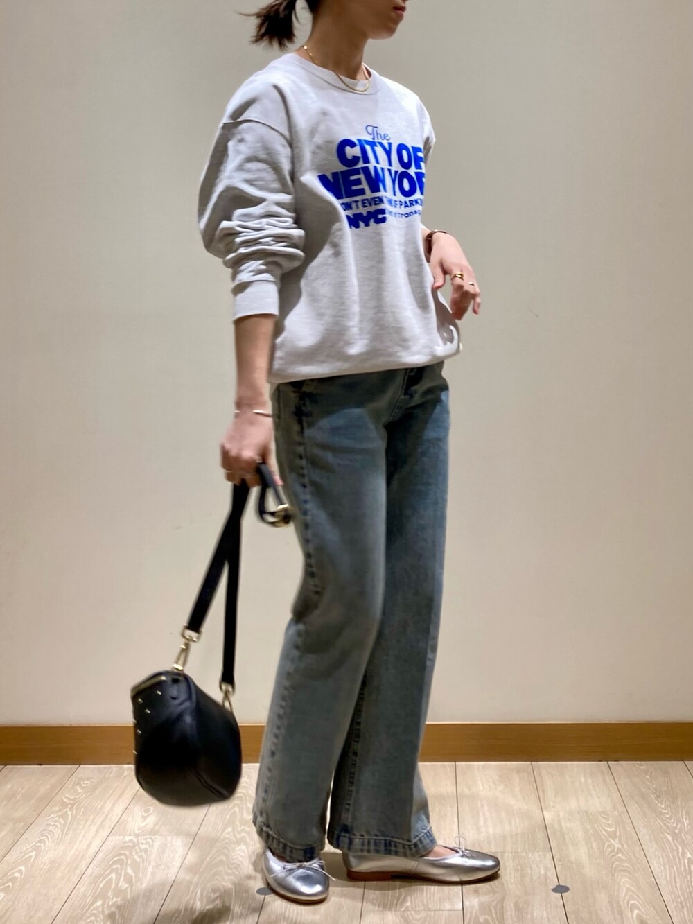 ブルー系のデニムパンツ、ブラック系のショルダーバッグ、シルバー系のバレエシューズを着用したレディースの冬コーディネートの3枚目の写真