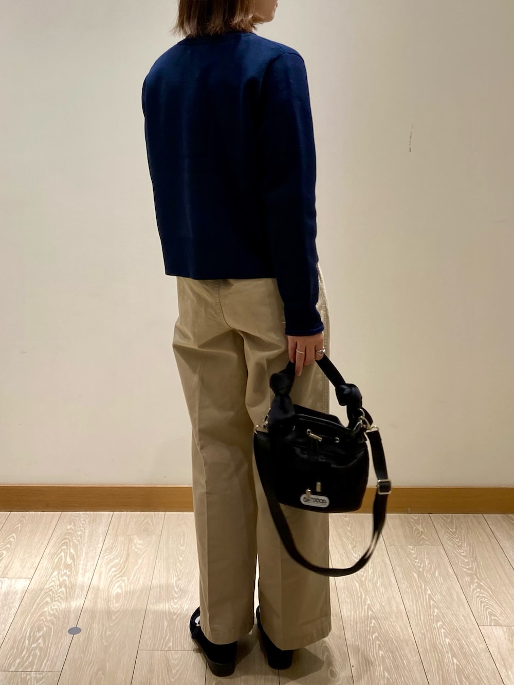 ブラック系のショルダーバッグ、ブルー系のカーディガン/ボレロ、ホワイト系のTシャツ/カットソーを着用したレディースの秋コーディネートの4枚目の写真