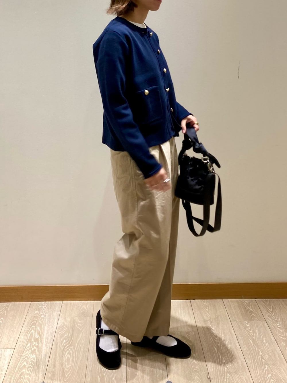 ブラック系のショルダーバッグ、ブルー系のカーディガン/ボレロ、ホワイト系のTシャツ/カットソーを着用したレディースの秋コーディネートの3枚目の写真