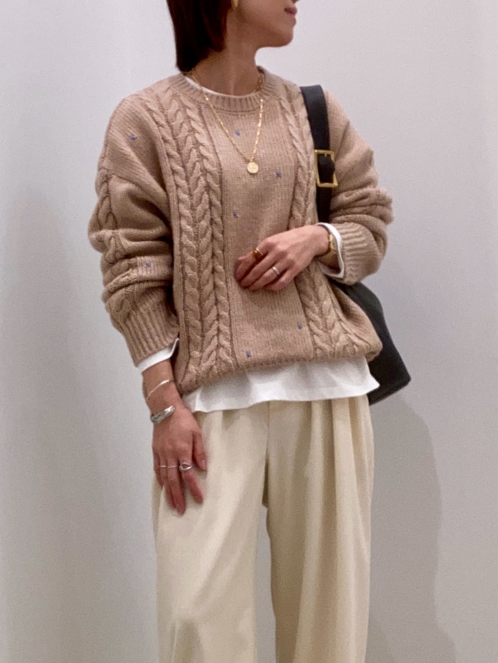 ベージュ系のニット/セーター、ホワイト系のTシャツ/カットソー、ブラック系のショルダーバッグを着用したレディースの秋コーディネートの8枚目の写真