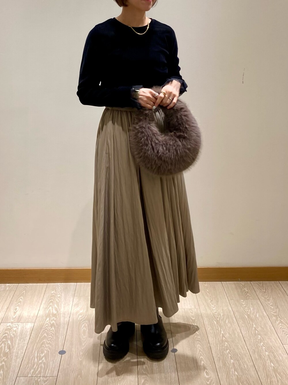 グレー系のハンドバッグ、ブラック系のブーツ、ブラック系のTシャツ/カットソーを着用したレディースの秋コーディネートの8枚目の写真