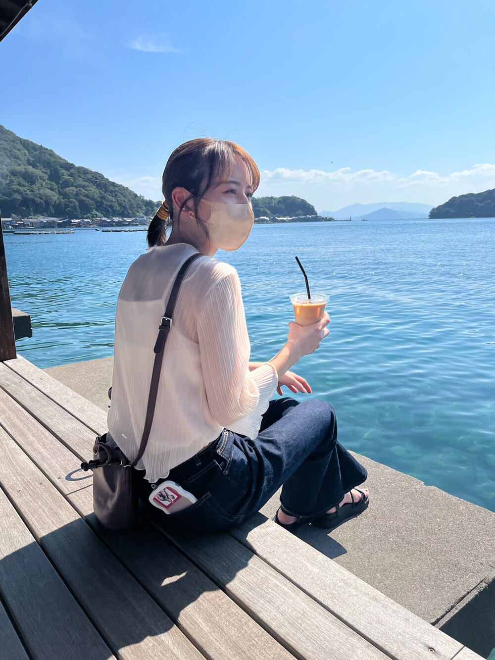 ブルー系のデニムパンツ、ホワイト系のシャツ/ブラウス、ブラック系のサンダルを着用したレディースの秋コーディネートの2枚目の写真