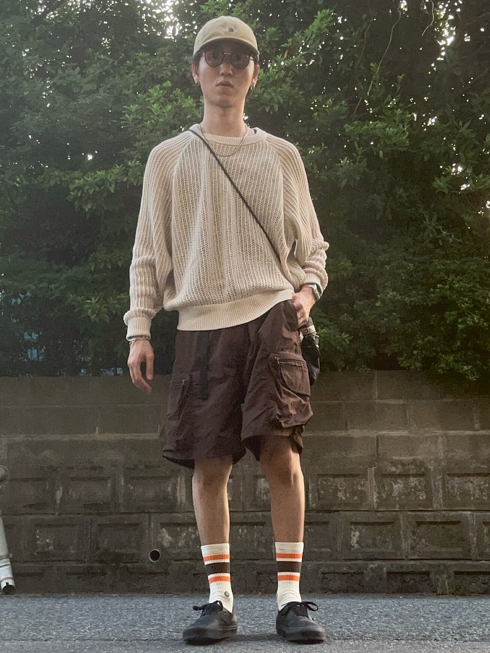 ベージュ系のニット/セーター、ブラウン系のパンツ、ブラック系のスニーカーを着用したメンズの夏コーディネートの2枚目の写真