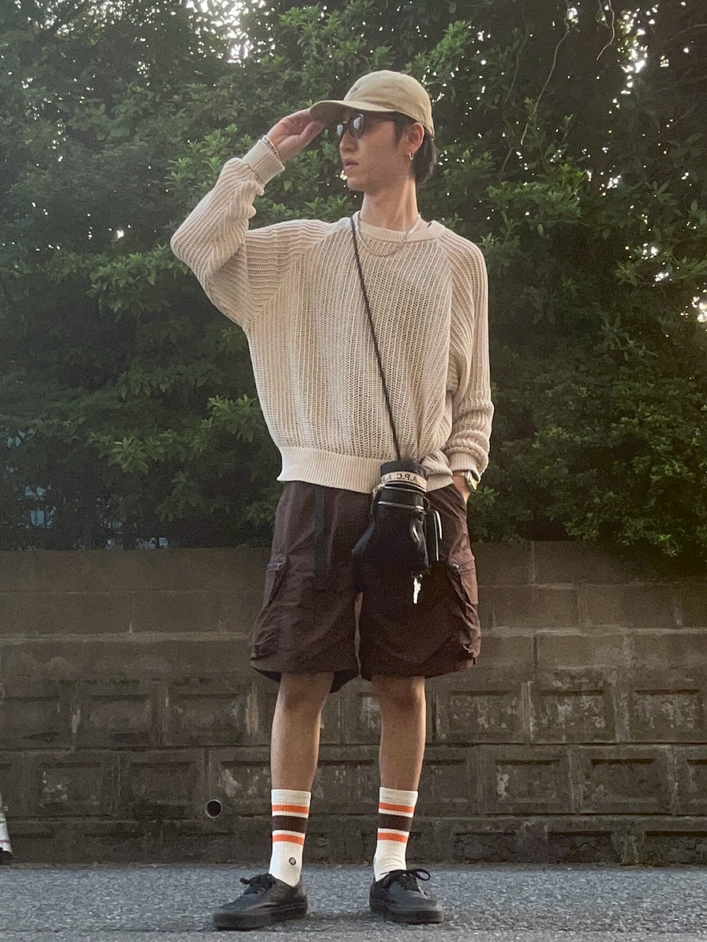 ベージュ系のニット/セーター、ブラウン系のパンツ、ブラック系のスニーカーを着用したメンズの夏コーディネートの3枚目の写真