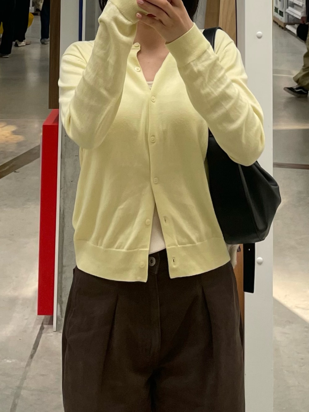 イエロー系のカーディガン/ボレロ、ブラウン系のデニムパンツ、ホワイト系のタンクトップを着用したレディースの春コーディネートの2枚目の写真