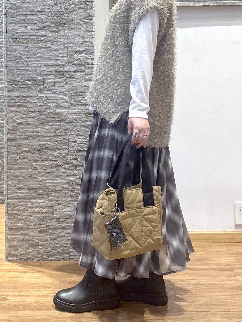 ブラウン系のトートバッグ、ブラウン系のスカート、ブラウン系のベストを着用したレディースの秋コーディネートの3枚目の写真