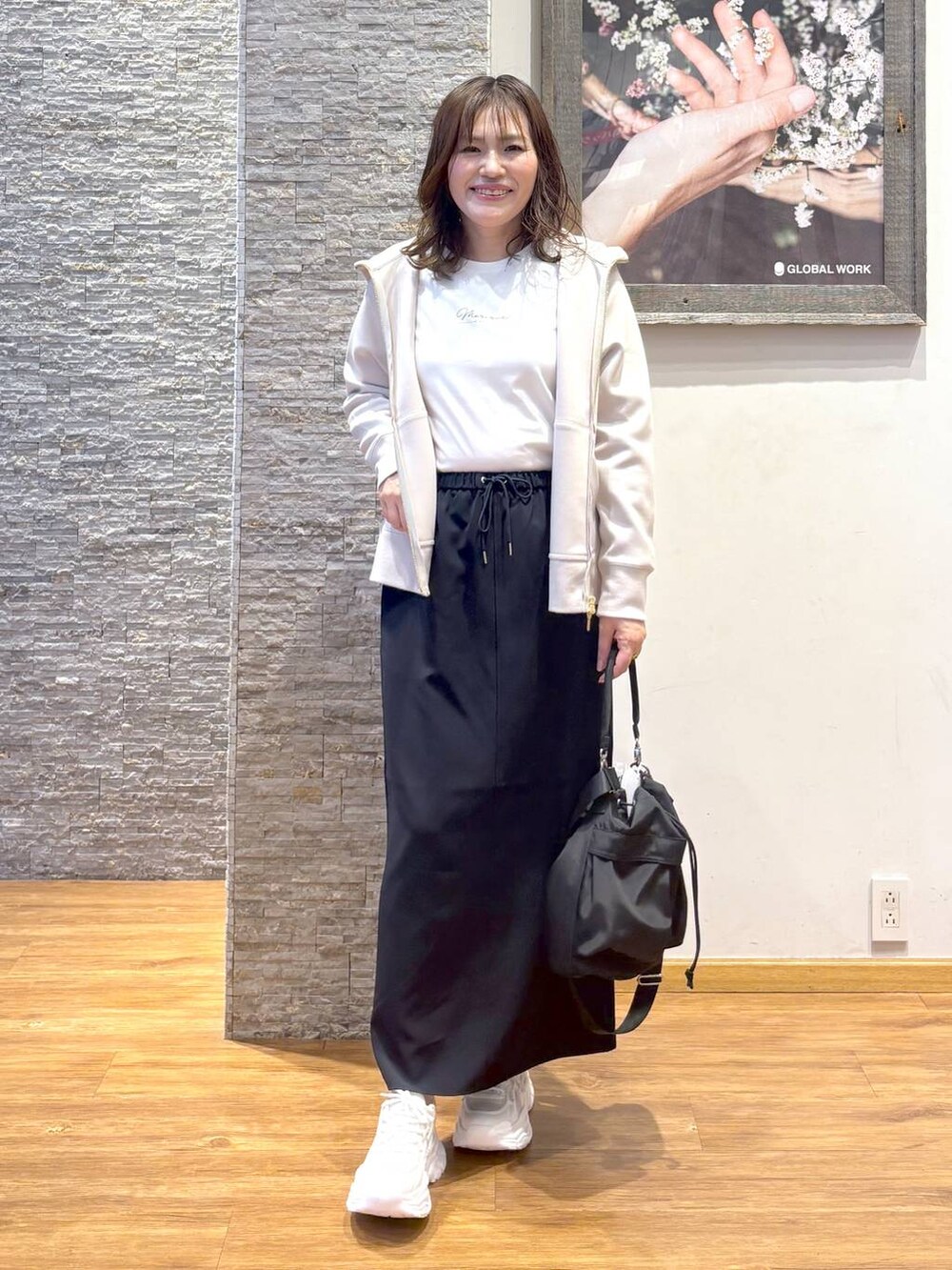 ホワイト系のショルダーバッグ、ブラック系のスカート、ホワイト系のスニーカーを着用したレディースの秋コーディネートの4枚目の写真