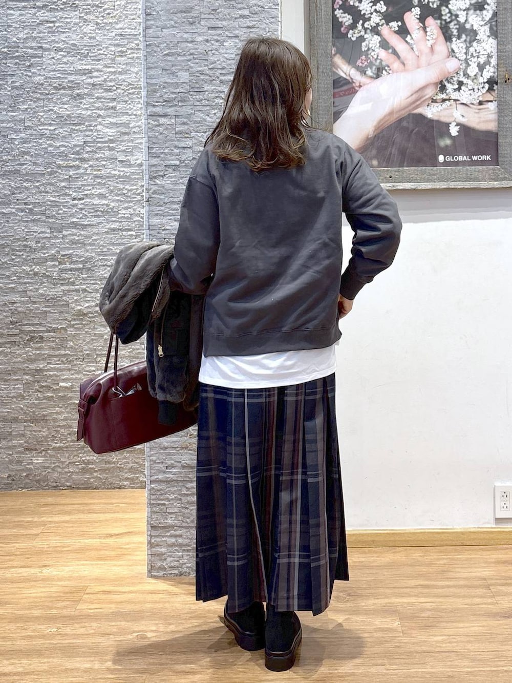 レッド系のボストンバッグ、ブラック系のブルゾン、ホワイト系のTシャツ/カットソーを着用したレディースの秋コーディネートの7枚目の写真