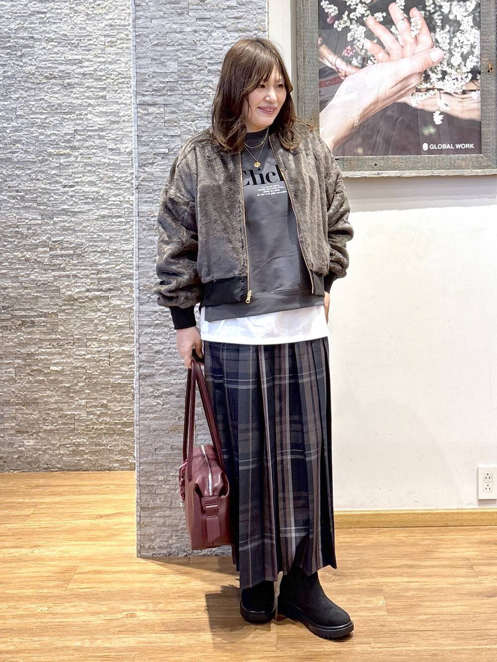 レッド系のボストンバッグ、ブラック系のブルゾン、ホワイト系のTシャツ/カットソーを着用したレディースの秋コーディネートの2枚目の写真