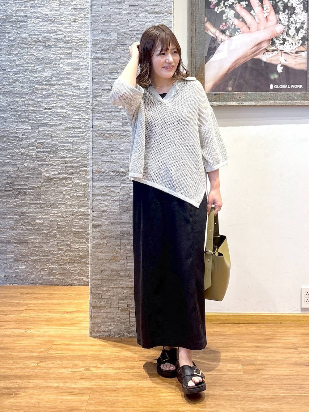 グリーン系のショルダーバッグ、ブラウン系のタンクトップ、ブラック系のサンダルを着用したレディースの夏コーディネートの2枚目の写真