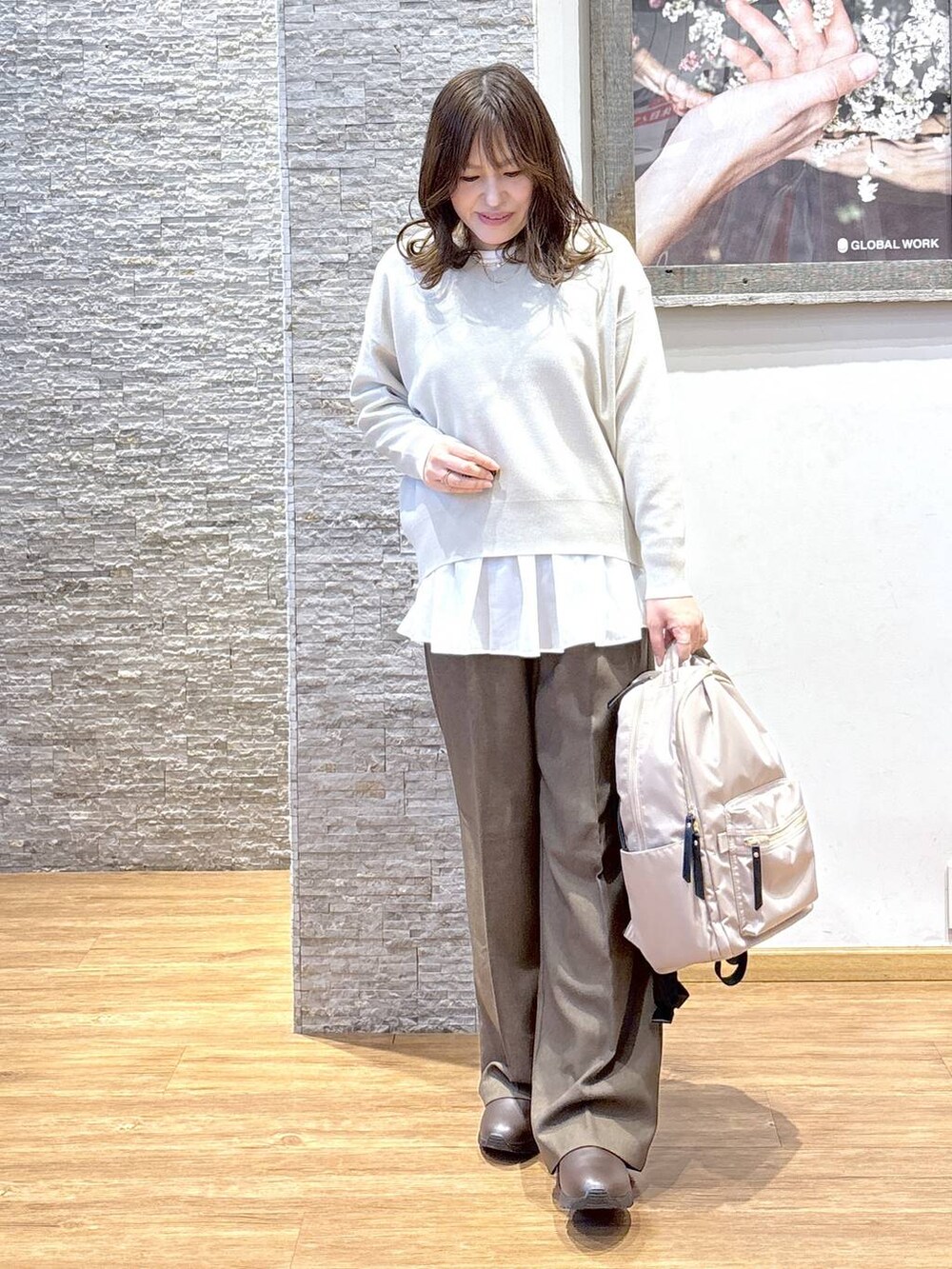 ブラック系のバックパック/リュック、ベージュ系のダウンジャケット/コート、ブラウン系のスウェットを着用したレディースの秋コーディネートの3枚目の写真