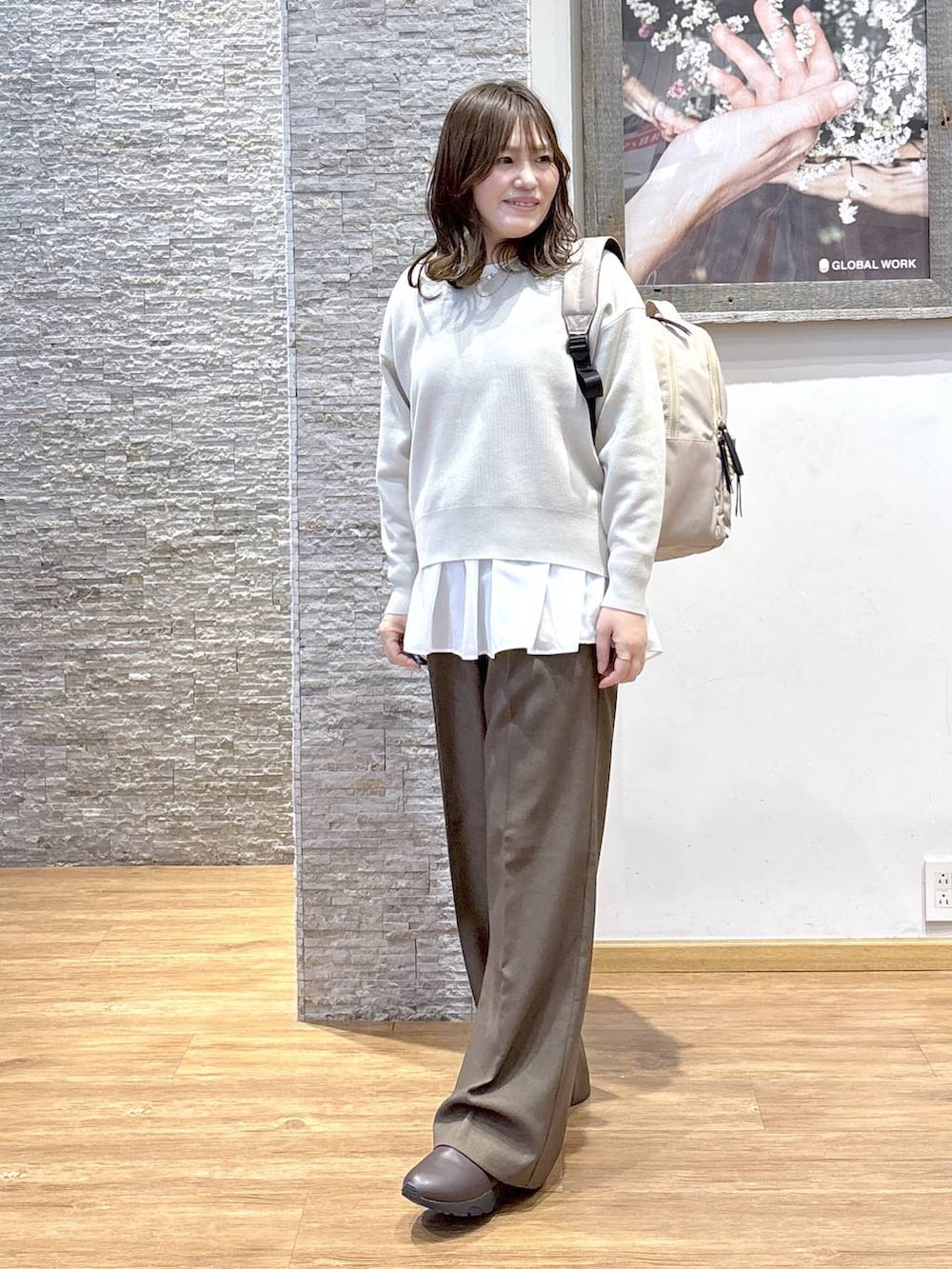 ブラック系のバックパック/リュック、ベージュ系のダウンジャケット/コート、ブラウン系のスウェットを着用したレディースの秋コーディネートの4枚目の写真