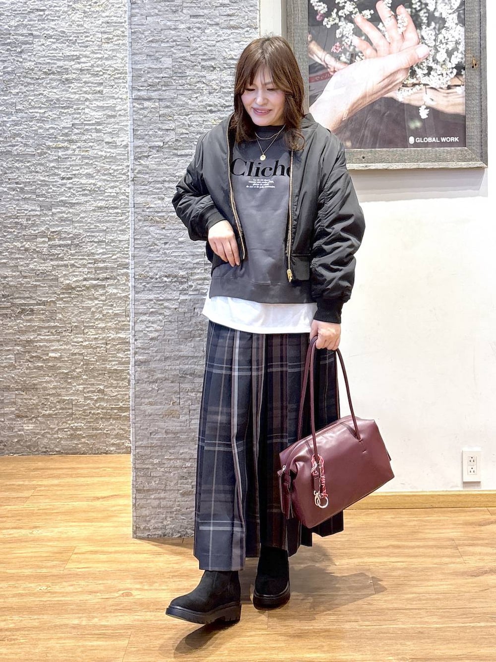 レッド系のボストンバッグ、ブラック系のブルゾン、ホワイト系のTシャツ/カットソーを着用したレディースの秋コーディネートの4枚目の写真