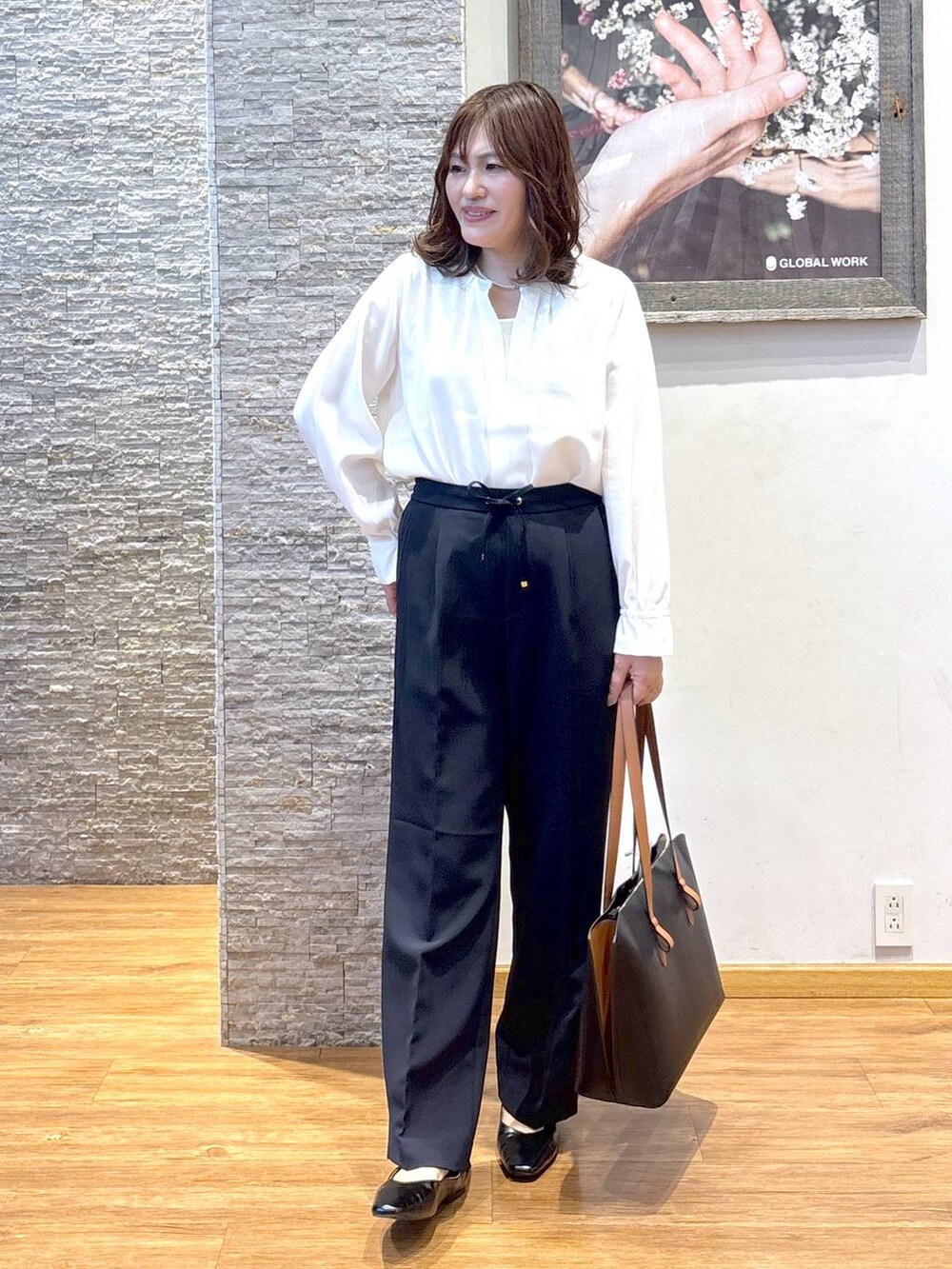 ブラック系のパンプス、ブラック系のトートバッグ、ブラック系のスラックスを着用したレディースの秋コーディネートの2枚目の写真