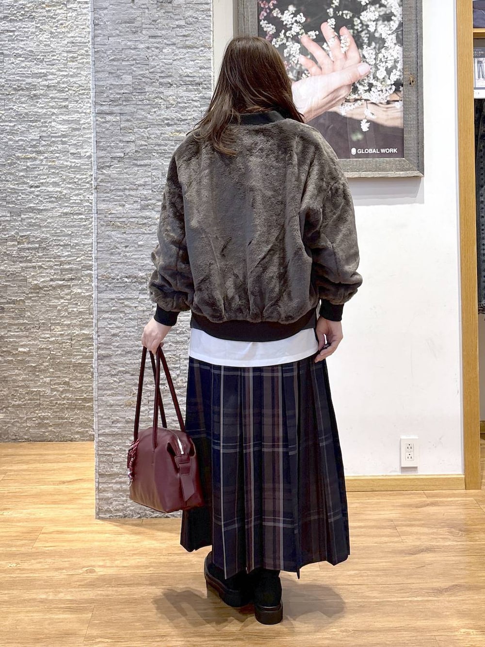 レッド系のボストンバッグ、ブラック系のブルゾン、ホワイト系のTシャツ/カットソーを着用したレディースの秋コーディネートの3枚目の写真