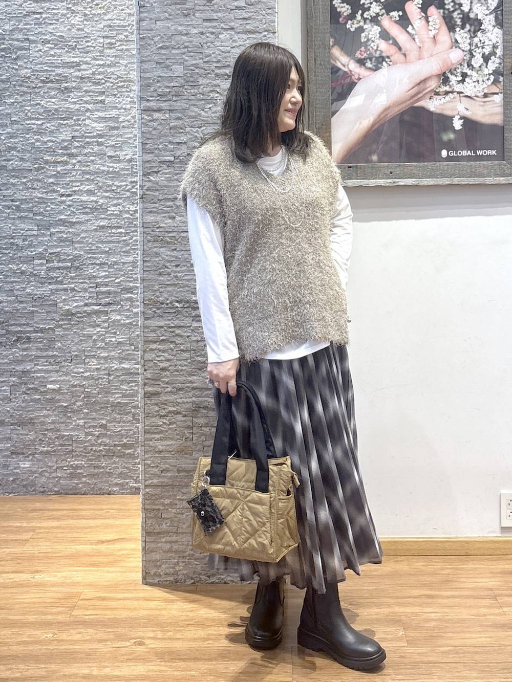 ブラウン系のトートバッグ、ブラウン系のスカート、ブラウン系のベストを着用したレディースの秋コーディネートの2枚目の写真