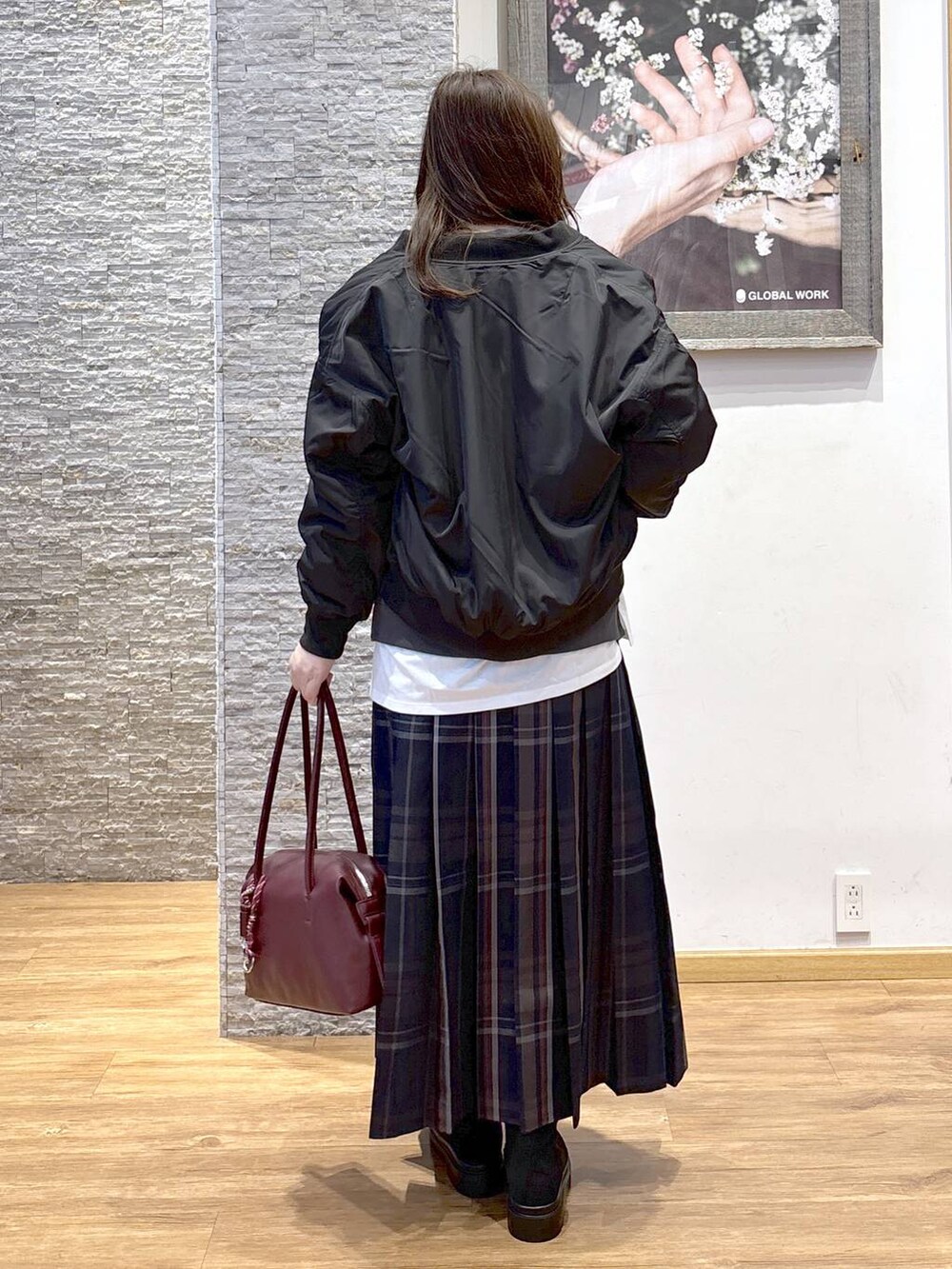 レッド系のボストンバッグ、ブラック系のブルゾン、ホワイト系のTシャツ/カットソーを着用したレディースの秋コーディネートの5枚目の写真