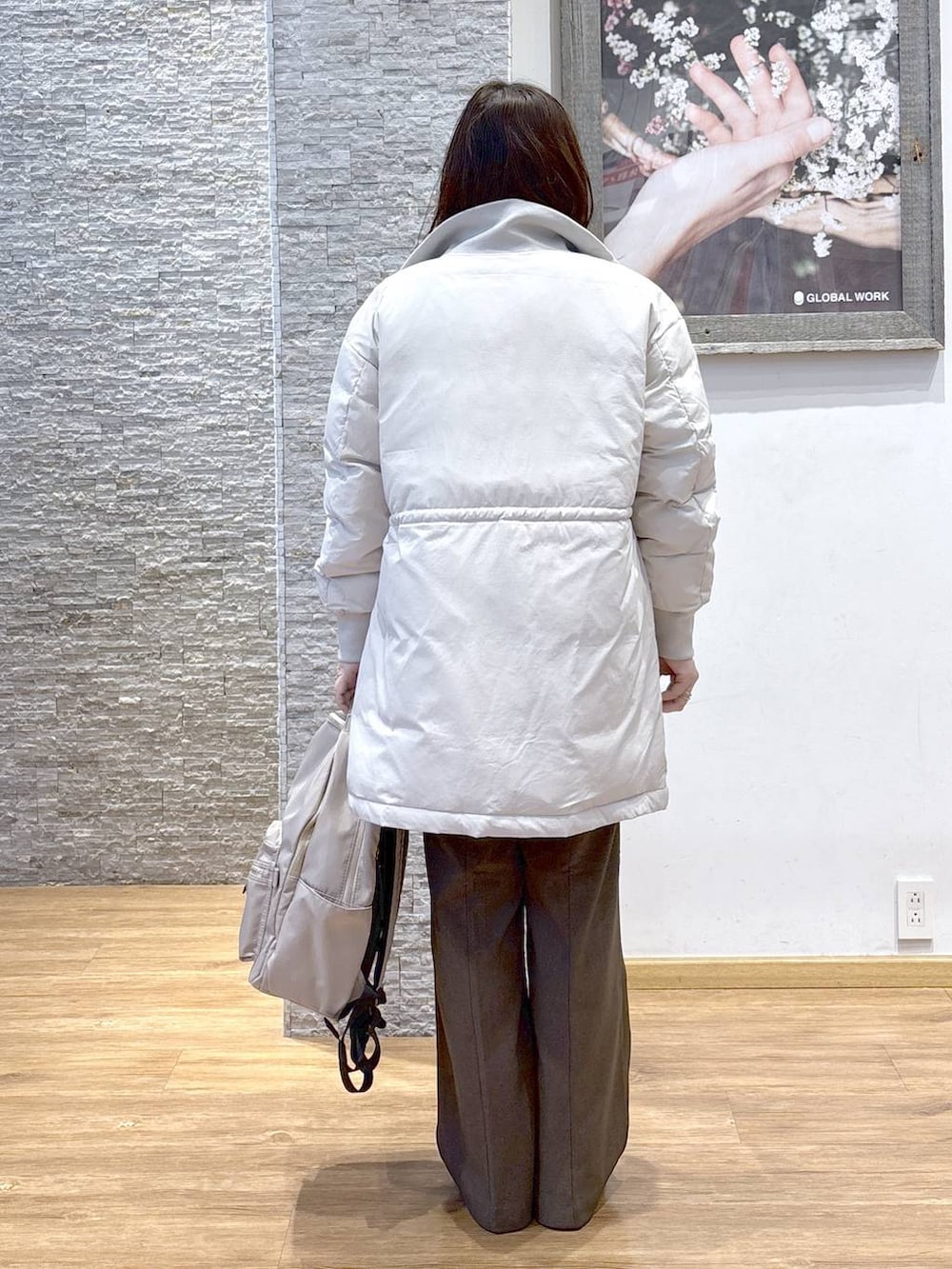 ブラック系のバックパック/リュック、ベージュ系のダウンジャケット/コート、ブラウン系のスウェットを着用したレディースの秋コーディネートの2枚目の写真