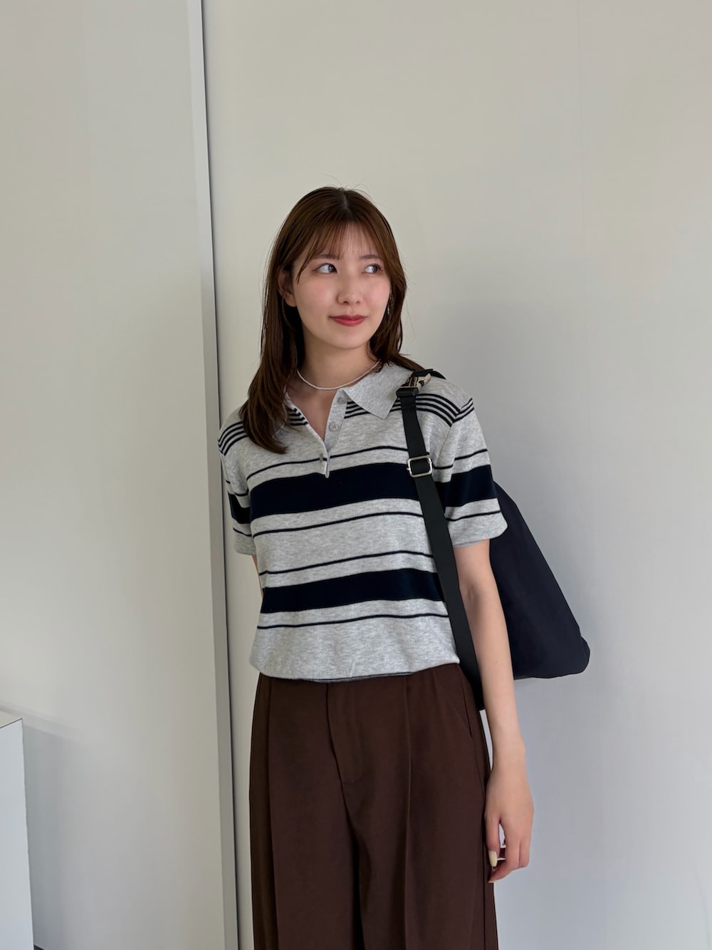 グレー系のニット/セーター、ブラウン系のスラックス、ブラック系のサンダルを着用したレディースの春コーディネートの3枚目の写真