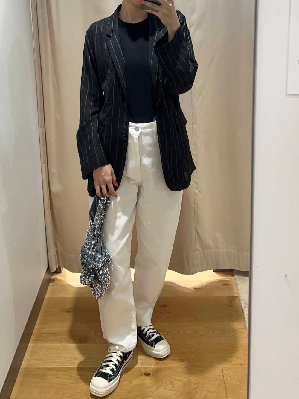 シルバー系のハンドバッグ、ブラック系のその他アウター、ホワイト系のデニムパンツを着用したレディースの夏コーディネートの4枚目の写真