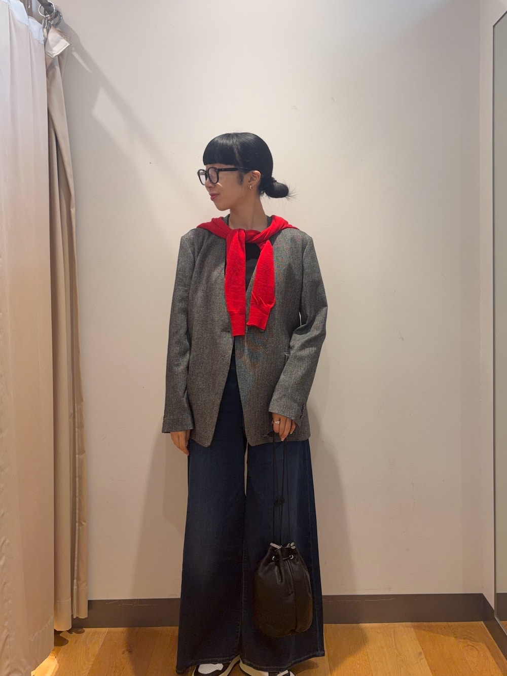 レッド系のカーディガン/ボレロ、ブルー系のデニムパンツ、ブラック系のショルダーバッグを着用したレディースの秋コーディネートの3枚目の写真