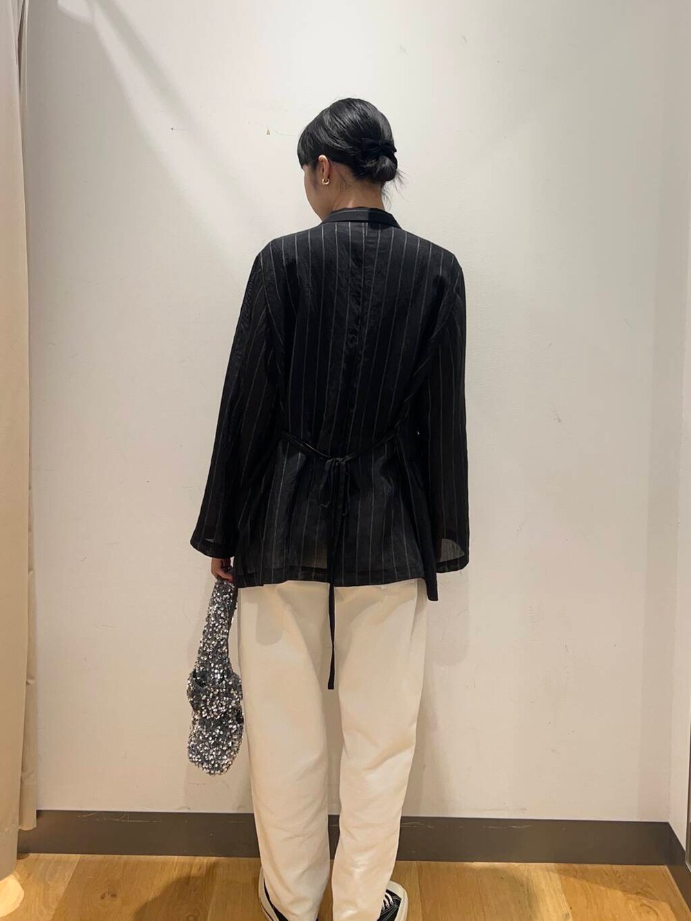 シルバー系のハンドバッグ、ブラック系のその他アウター、ホワイト系のデニムパンツを着用したレディースの夏コーディネートの3枚目の写真